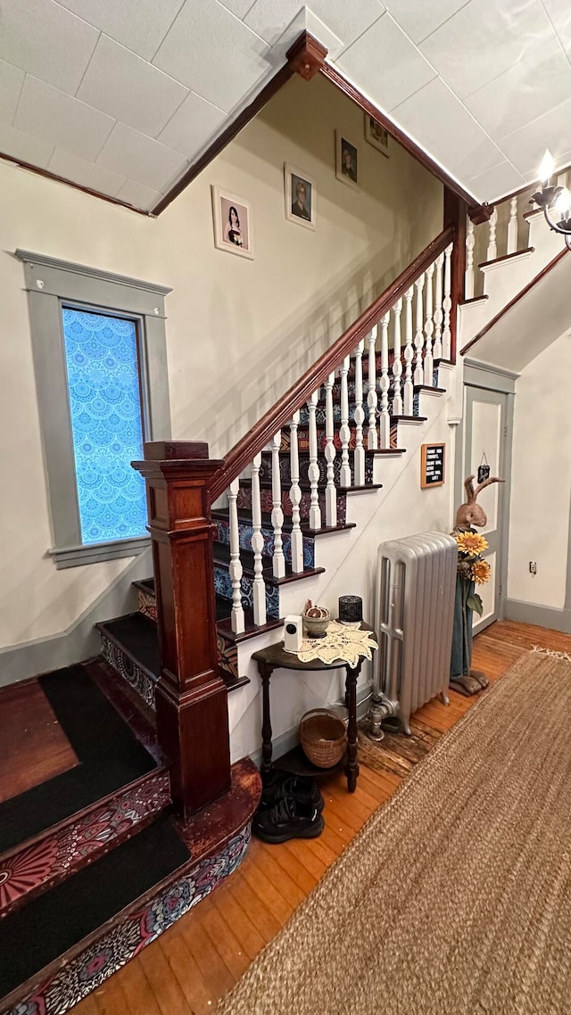 stairs featuring wood-type flooring and radiator heating unit