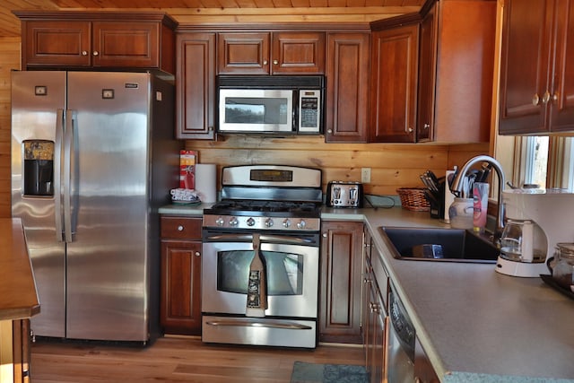 kitchen with sink, appliances with stainless steel finishes, wood ceiling, and wooden walls