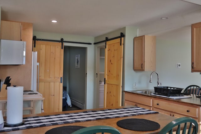 kitchen featuring white fridge, a barn door, sink, and light brown cabinetry