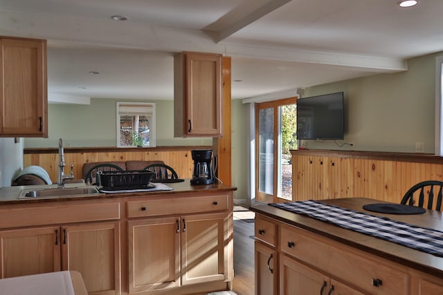 kitchen with beam ceiling, sink, light brown cabinetry, and wood-type flooring