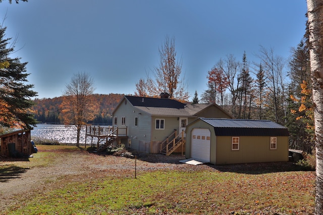 back of property featuring a deck with water view, a lawn, and a garage