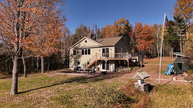 back of house featuring a playground, a deck, and a lawn