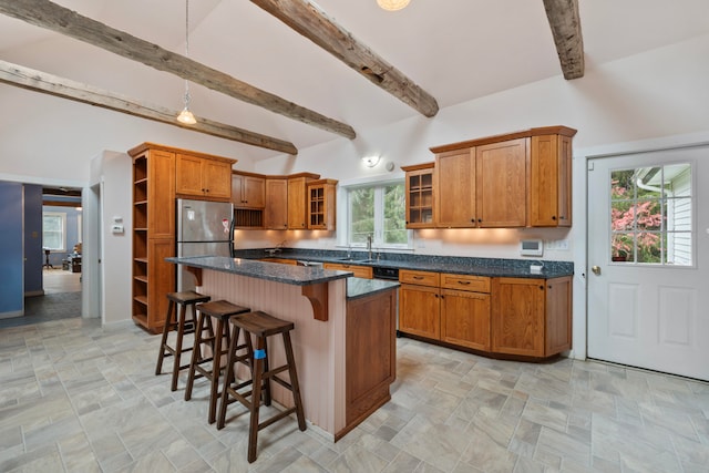 kitchen with stainless steel fridge, a kitchen island, a kitchen bar, dark stone countertops, and beamed ceiling