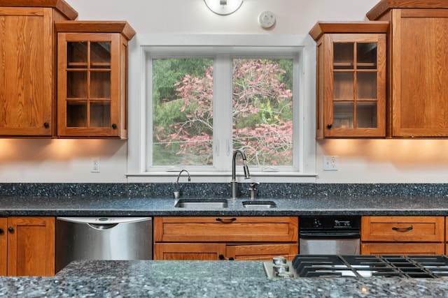 kitchen with sink, dishwasher, and dark stone counters