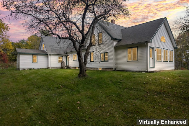 back house at dusk with a lawn