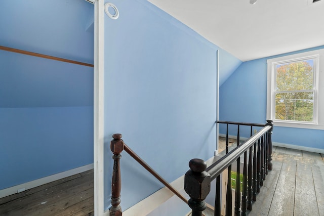 stairway with wood-type flooring and vaulted ceiling