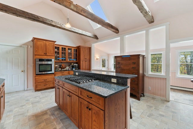 kitchen featuring a kitchen island, appliances with stainless steel finishes, a breakfast bar, dark stone countertops, and a skylight