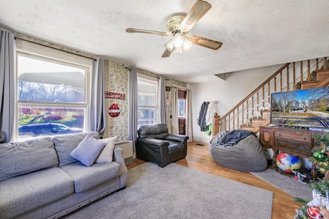 living room featuring stairs, a ceiling fan, a textured ceiling, and wood finished floors