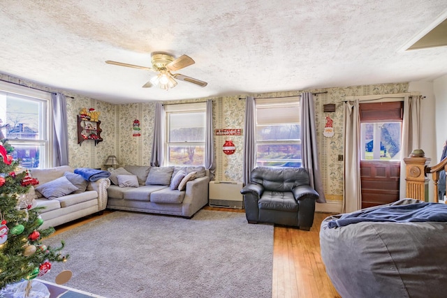 living area with light wood-style flooring, stairway, a textured ceiling, and wallpapered walls