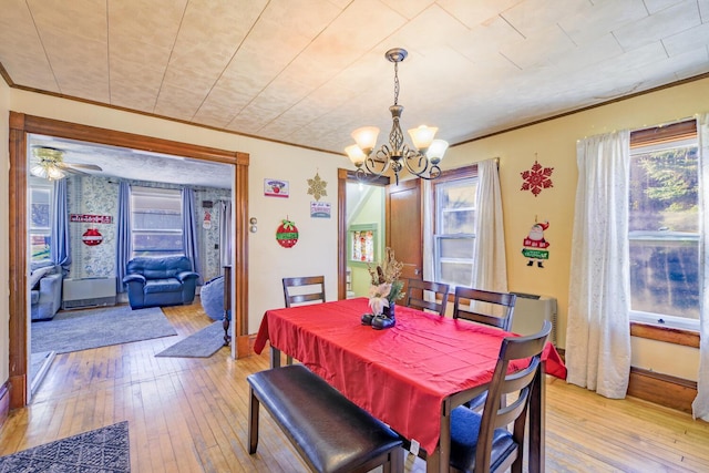 dining space featuring light wood finished floors, baseboards, ornamental molding, and an inviting chandelier