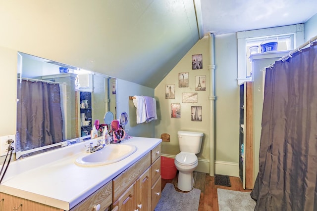 bathroom with baseboards, toilet, wood finished floors, vaulted ceiling, and vanity