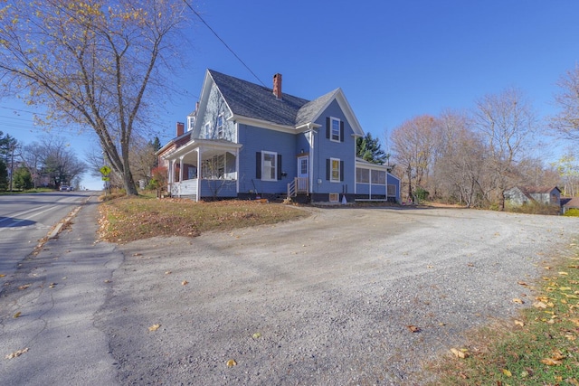 view of side of property with a porch and a chimney