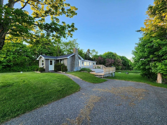 46 S Lubec Rd, Lubec, ME 04652 - view of front facade featuring a chimney, a front yard, a wooden deck, and view of wooded area