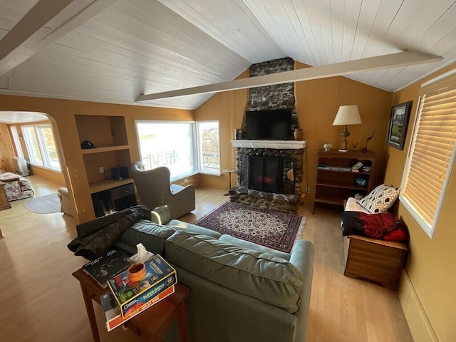 living room featuring vaulted ceiling, plenty of natural light, a stone fireplace, and light wood-type flooring