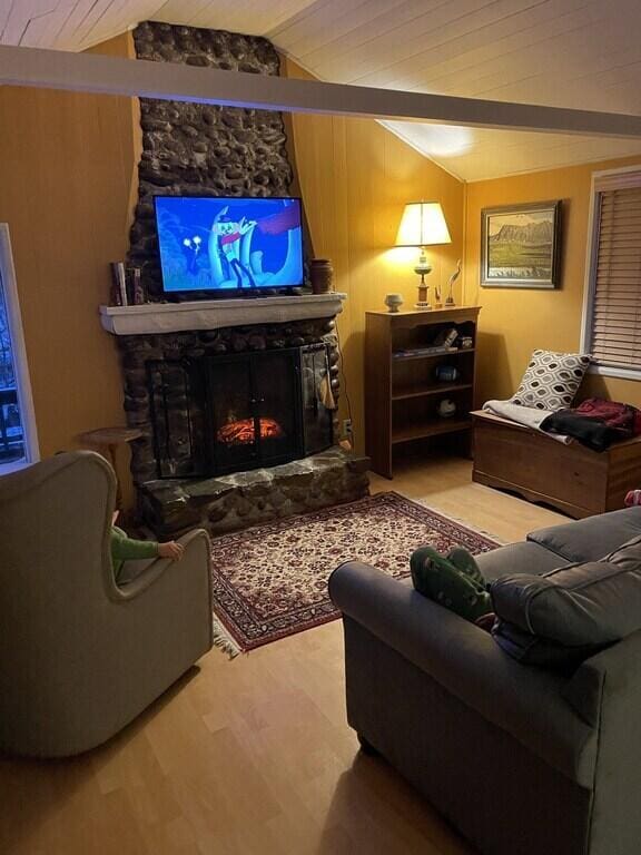 living room featuring wood ceiling, hardwood / wood-style floors, a fireplace, vaulted ceiling, and wood walls