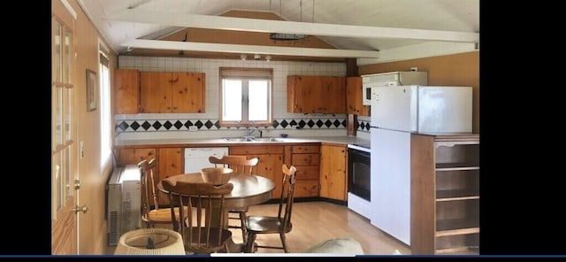 kitchen with tasteful backsplash, lofted ceiling, sink, light hardwood / wood-style floors, and white appliances