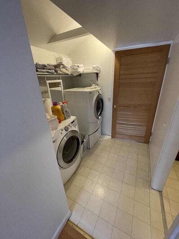 clothes washing area with light tile patterned floors and washer and clothes dryer