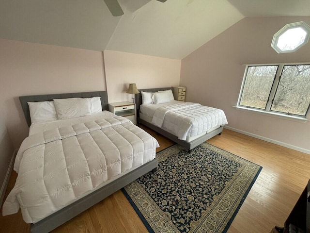 bedroom with ceiling fan, vaulted ceiling, and hardwood / wood-style floors