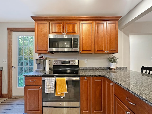 kitchen featuring dark stone countertops, appliances with stainless steel finishes, and a breakfast bar area