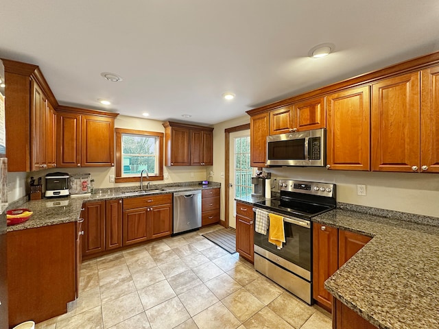 kitchen featuring light tile patterned floors, appliances with stainless steel finishes, sink, and dark stone counters