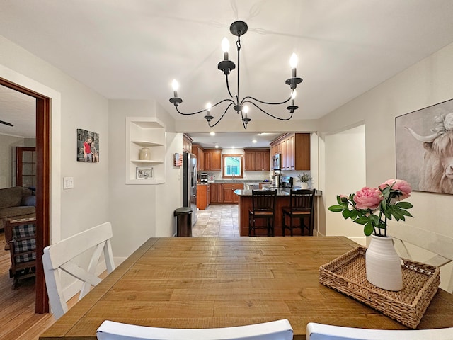 dining room featuring a notable chandelier, built in shelves, and light hardwood / wood-style floors