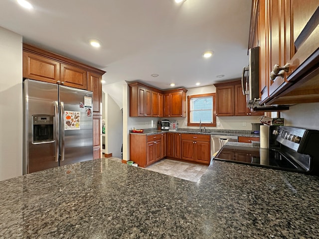 kitchen with sink, stainless steel appliances, and dark stone countertops