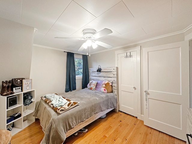 bedroom with crown molding, wood-type flooring, and ceiling fan