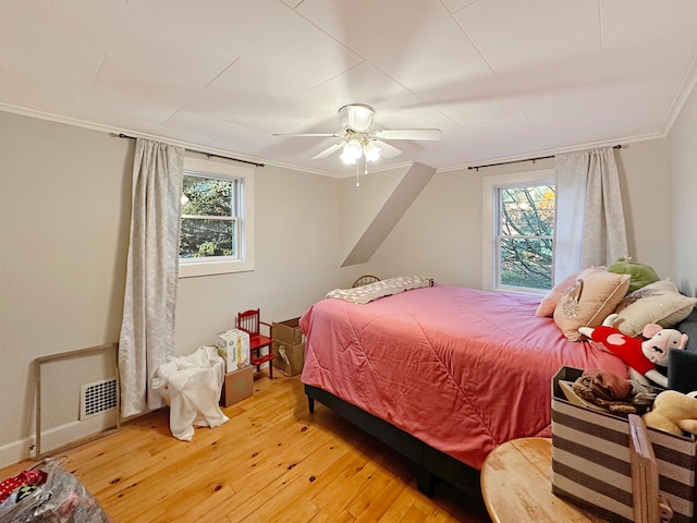 bedroom featuring ornamental molding, multiple windows, hardwood / wood-style flooring, and ceiling fan