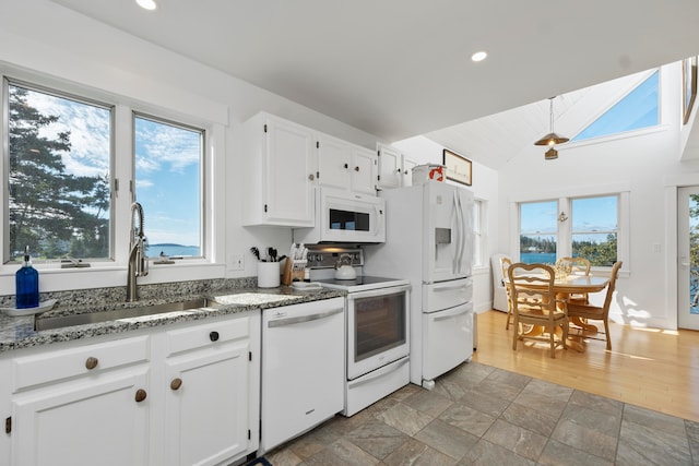 kitchen with a wealth of natural light, lofted ceiling, white cabinetry, and white appliances