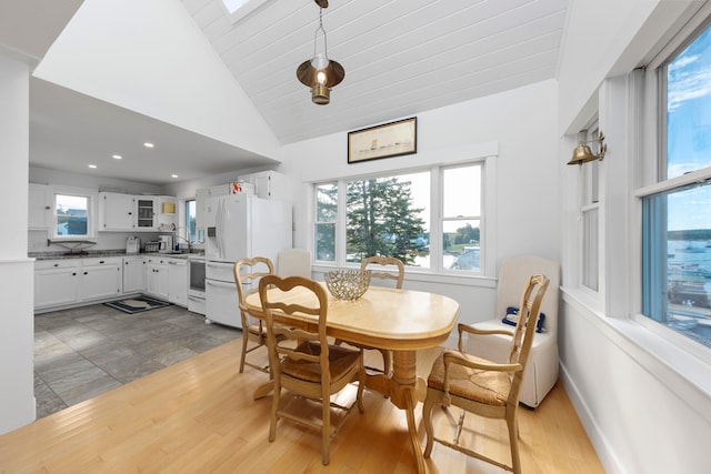 dining space featuring high vaulted ceiling, sink, and hardwood / wood-style floors