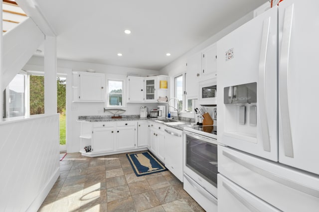 kitchen featuring white appliances, light stone counters, sink, and white cabinets