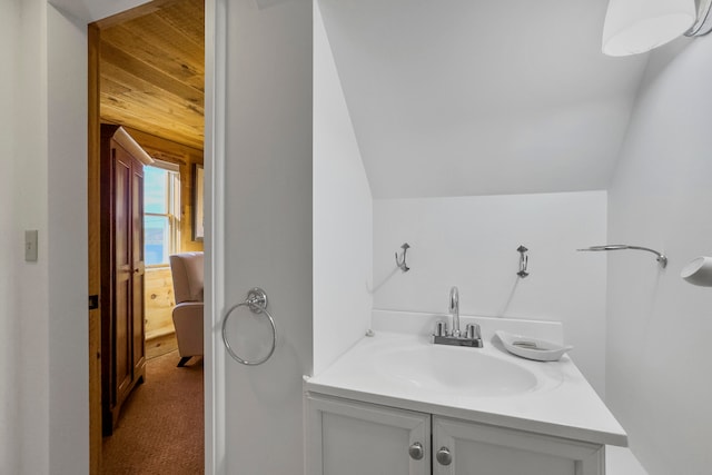 bathroom featuring vanity, wood walls, and vaulted ceiling