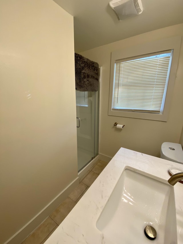 full bath featuring a stall shower, toilet, baseboards, a sink, and tile patterned flooring