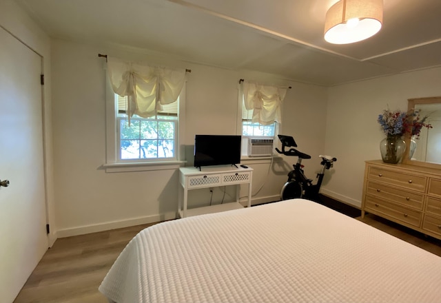 bedroom with baseboards, multiple windows, cooling unit, and wood finished floors