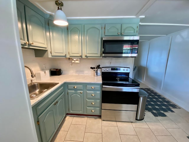 kitchen featuring stainless steel appliances, sink, green cabinetry, and decorative light fixtures