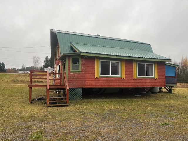 rear view of property featuring a wooden deck and a lawn