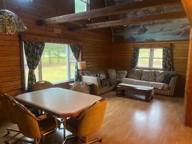 dining room featuring light hardwood / wood-style flooring, wood walls, and beam ceiling