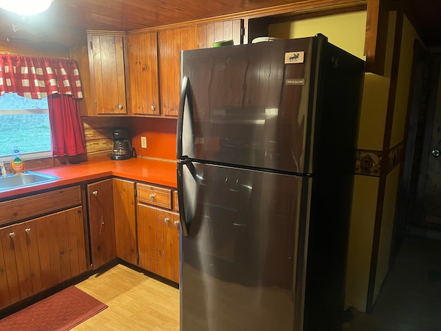 kitchen featuring wooden ceiling, sink, light wood-type flooring, and stainless steel fridge