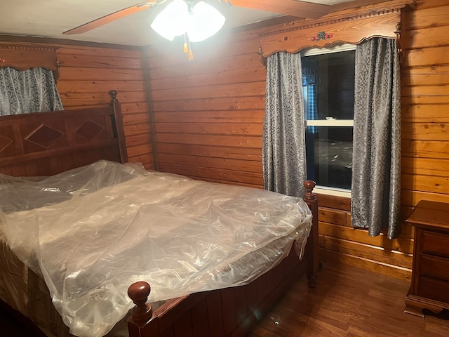 bedroom featuring dark wood-type flooring, ceiling fan, and wooden walls