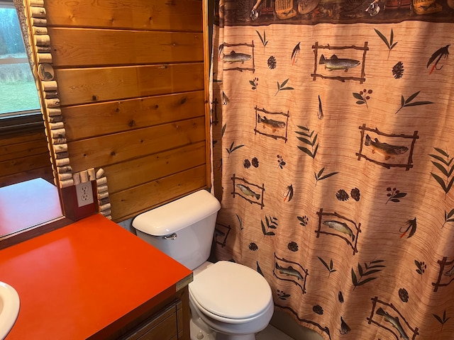 bathroom featuring vanity, wooden walls, a shower with shower curtain, and toilet