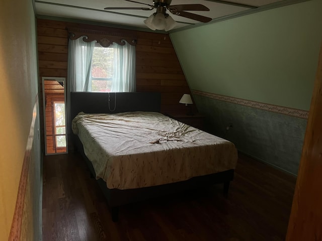 bedroom featuring wood walls, dark hardwood / wood-style floors, and ceiling fan