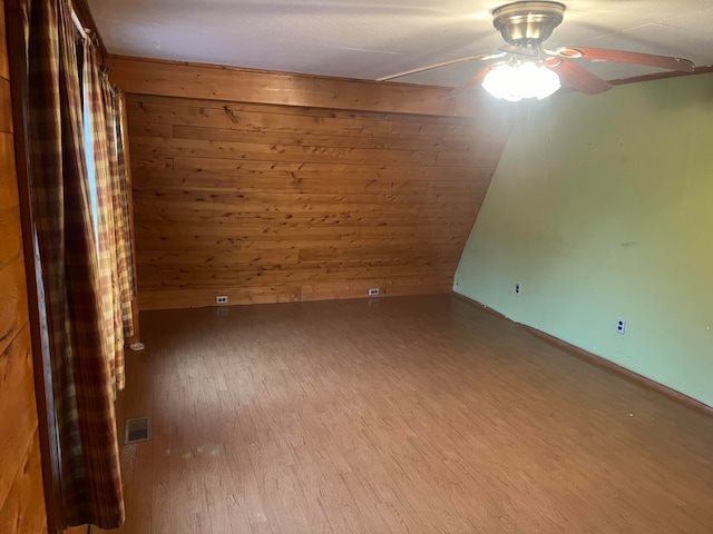 spare room with wood walls, hardwood / wood-style flooring, and ceiling fan