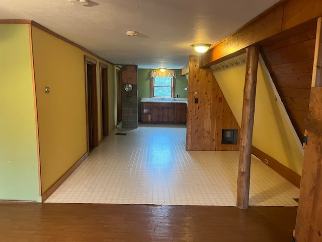 hallway with a textured ceiling, wooden walls, and light tile patterned floors