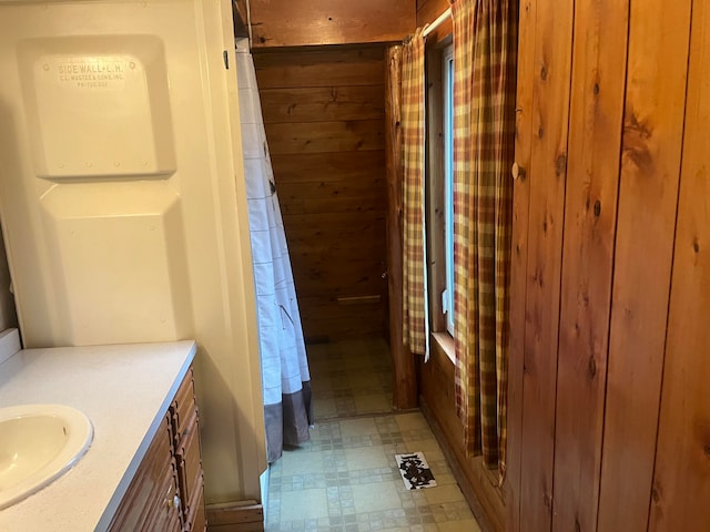 bathroom featuring vanity, wooden walls, and a shower with shower curtain