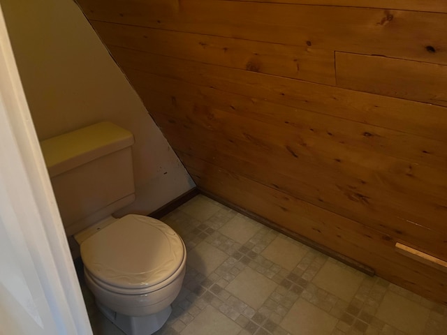 bathroom with toilet and wood walls