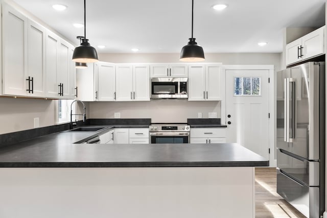 kitchen with white cabinetry, stainless steel appliances, sink, and pendant lighting