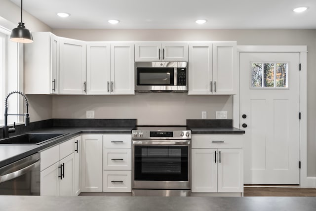 kitchen with white cabinetry, stainless steel appliances, sink, and pendant lighting