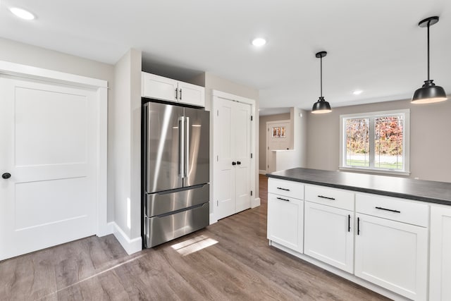 kitchen with high quality fridge, hardwood / wood-style floors, white cabinetry, and hanging light fixtures