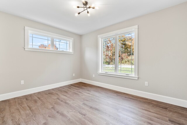 unfurnished room with a notable chandelier and light hardwood / wood-style flooring