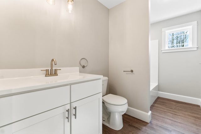 bathroom with toilet, vanity, wood-type flooring, and a bathtub